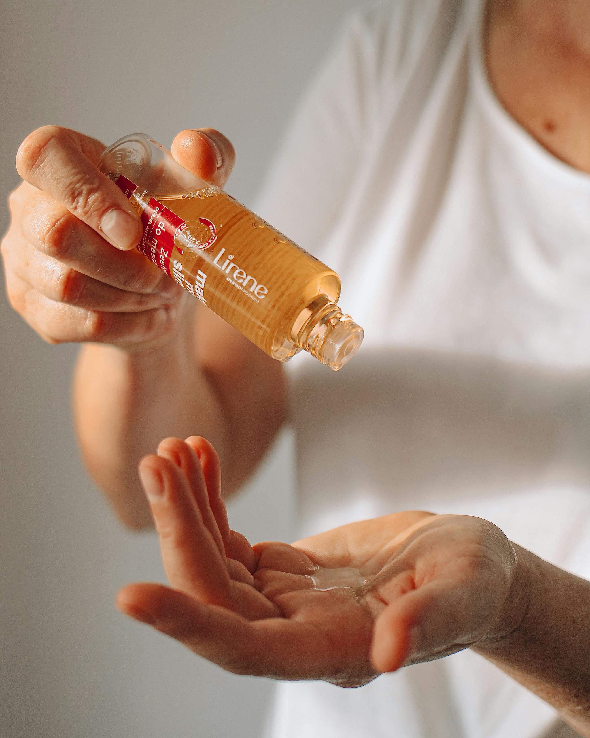Detailed image of hands pouring Lirene massage oil, ideal for beauty and wellness themes.