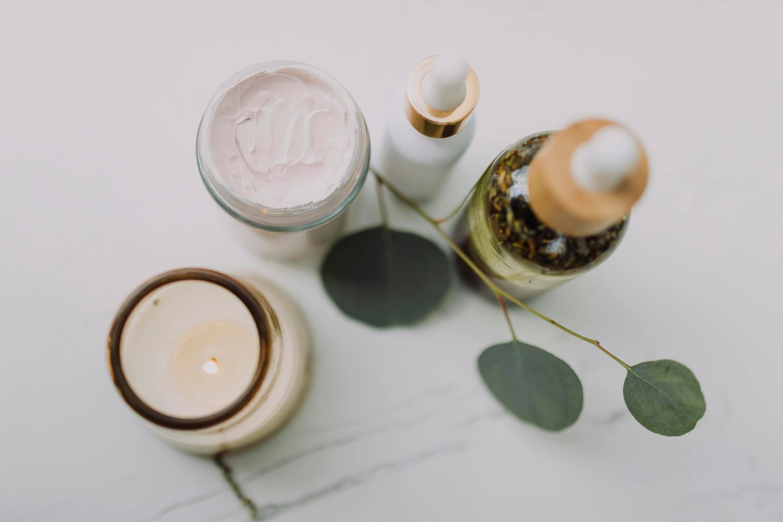 Calming spa scene featuring skincare items, a candle, and eucalyptus leaves for relaxation.