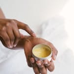 Close-up of a hand applying natural skincare cream, emphasizing self-care and holistic health.