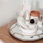 Stylish arrangement of beauty products on a wooden table with a mirror tray, creating an aesthetic display.