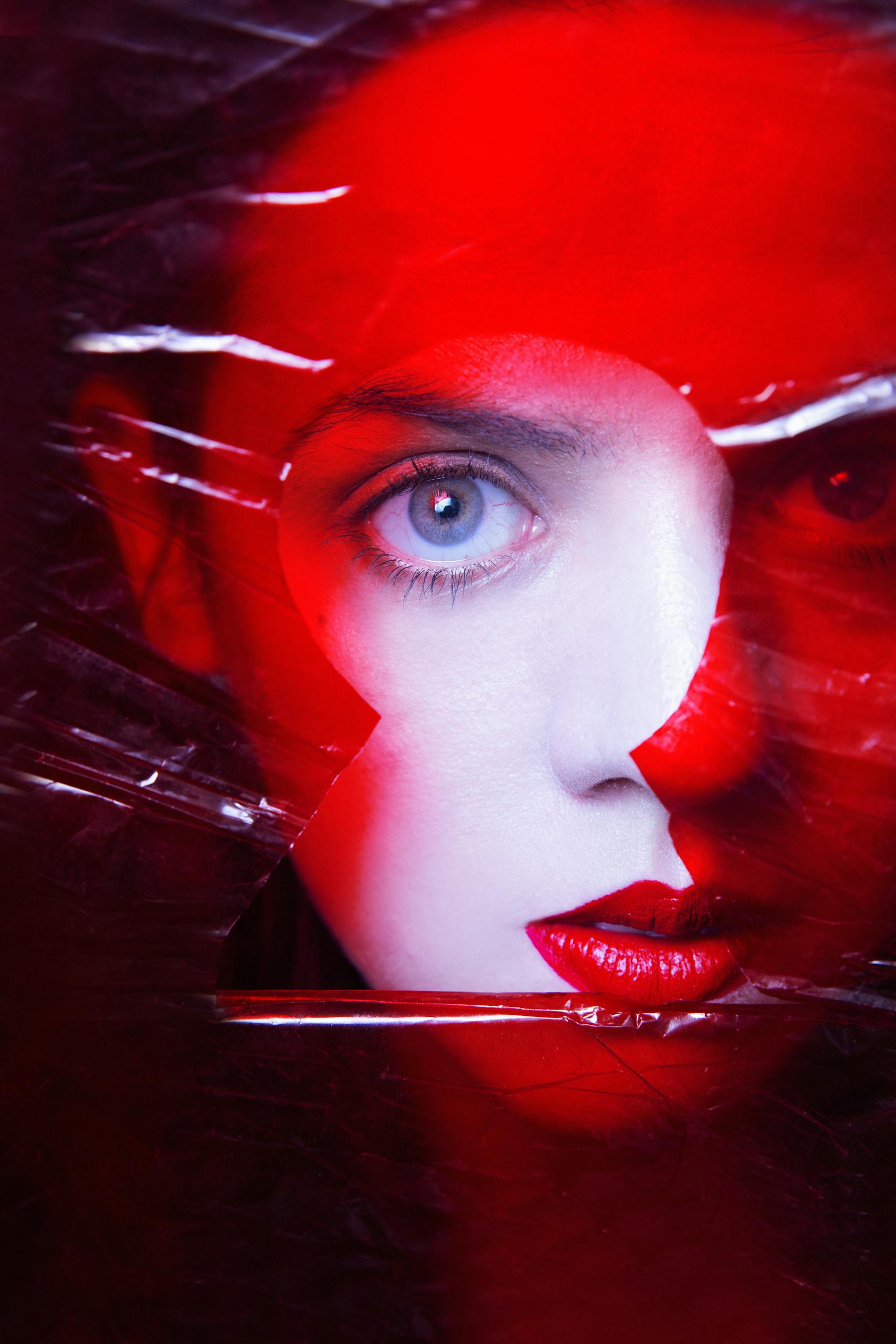 Artistic portrait of a woman with vivid red hues and striking eye detail.