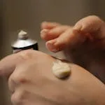 Close-up of hands applying skincare cream, highlighting self-care routine.