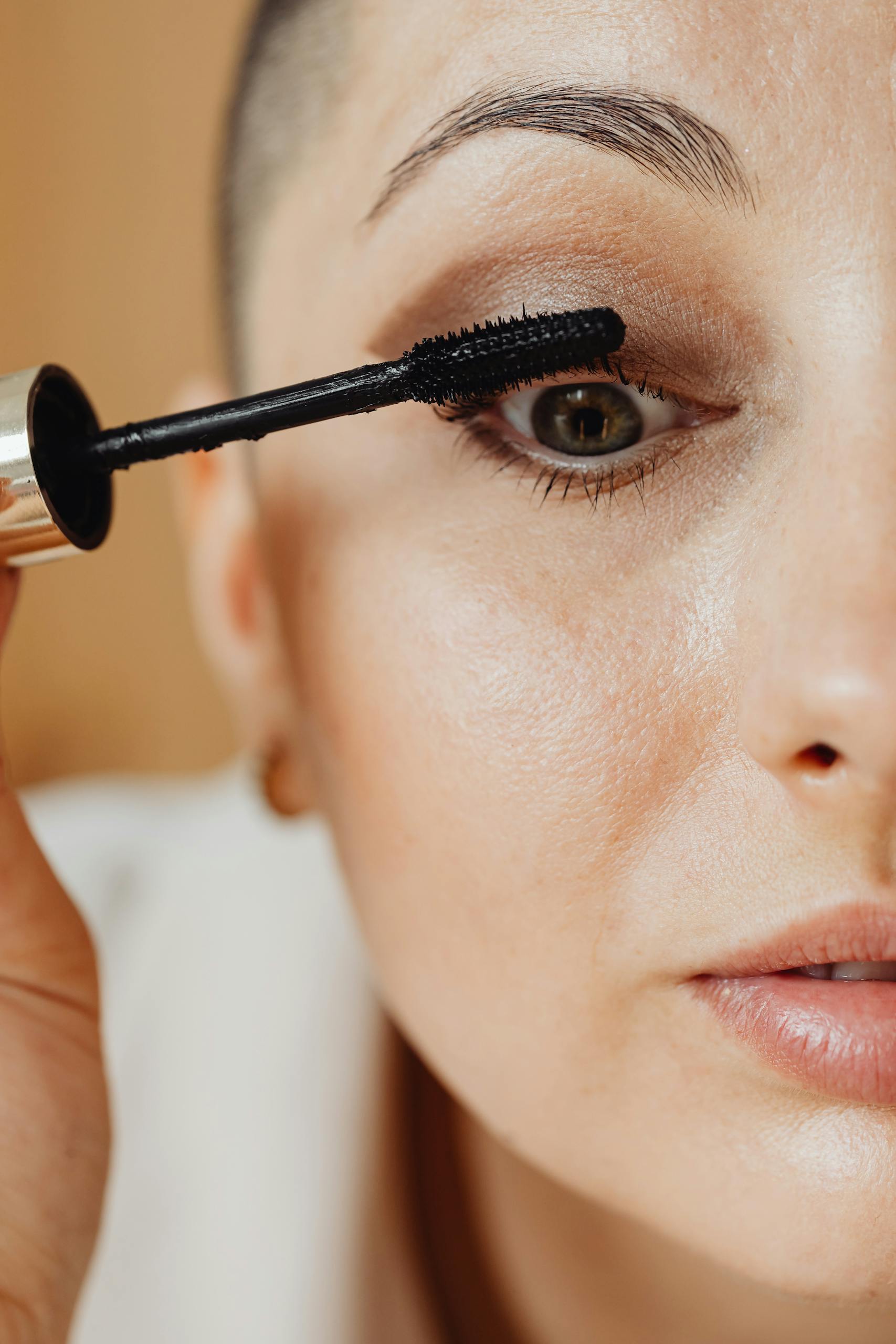 Detailed view of a woman applying mascara, highlighting makeup and beauty routines.