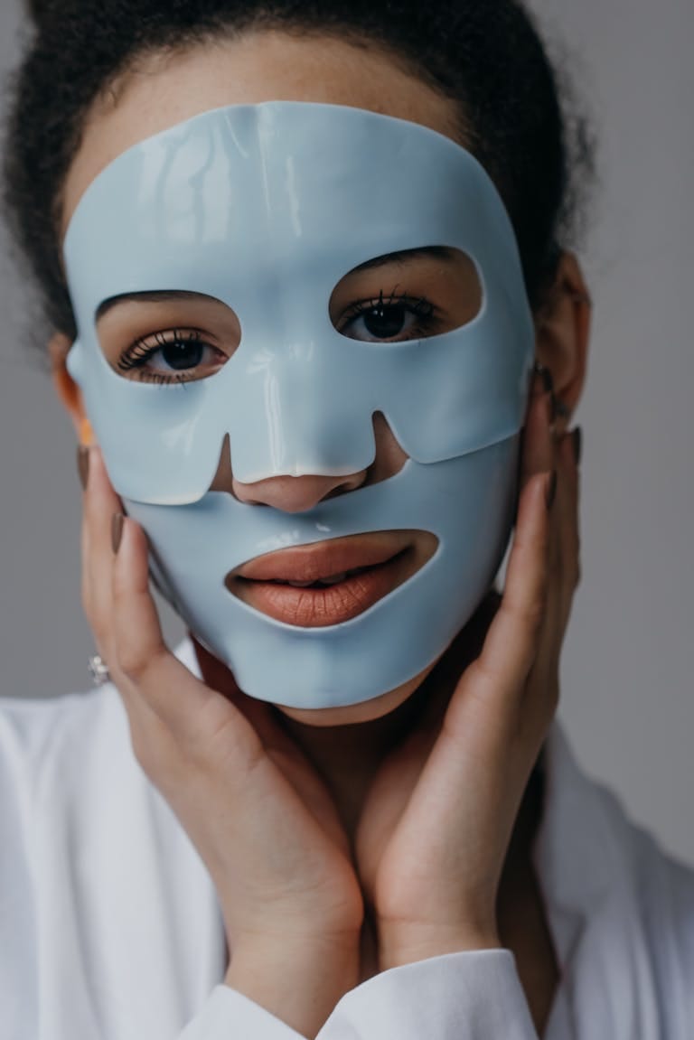 A close-up portrait of a woman wearing a blue skincare face mask, emphasizing self-care and beauty.