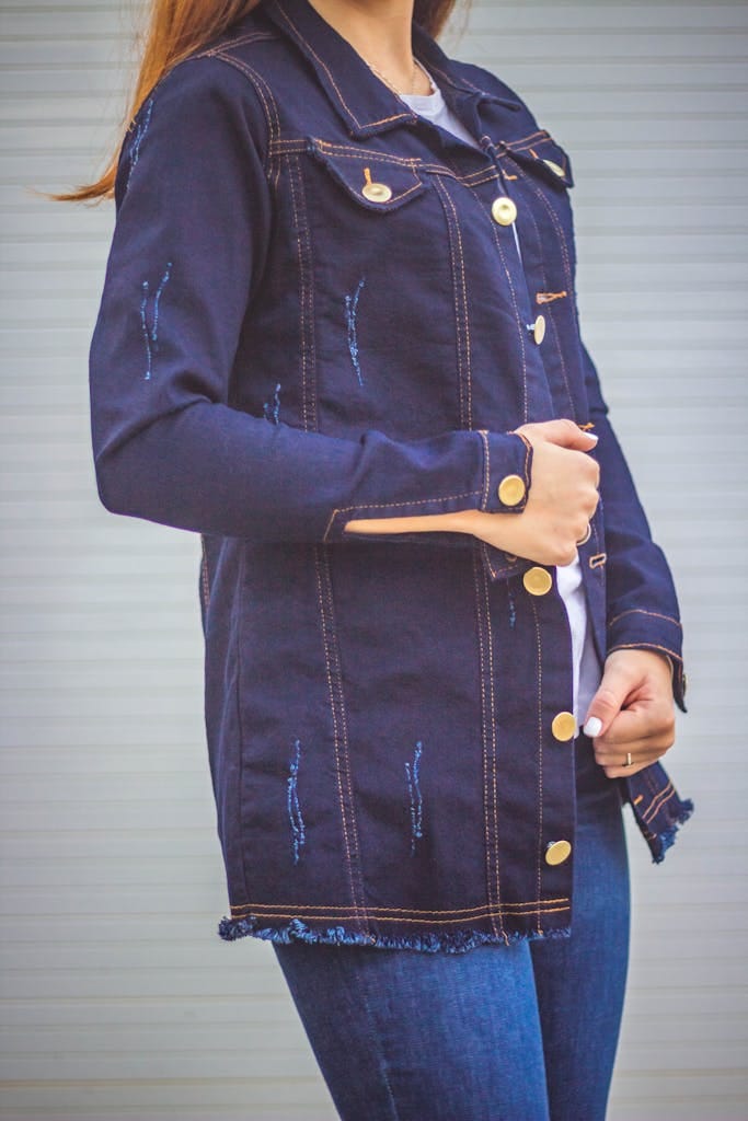 Fashionable woman showcasing a denim jacket in an outdoor setting.