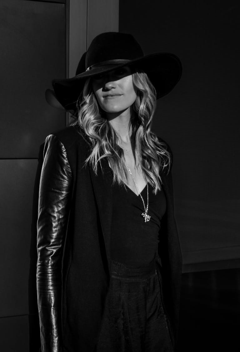 A fashionable woman in chic attire and hat, captured in a stylish black and white portrait.