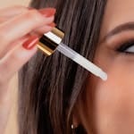 A woman applies skincare serum using a dropper for healthy skin beauty routine.