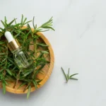Rosemary oil bottle with fresh rosemary leaves for hair growth.